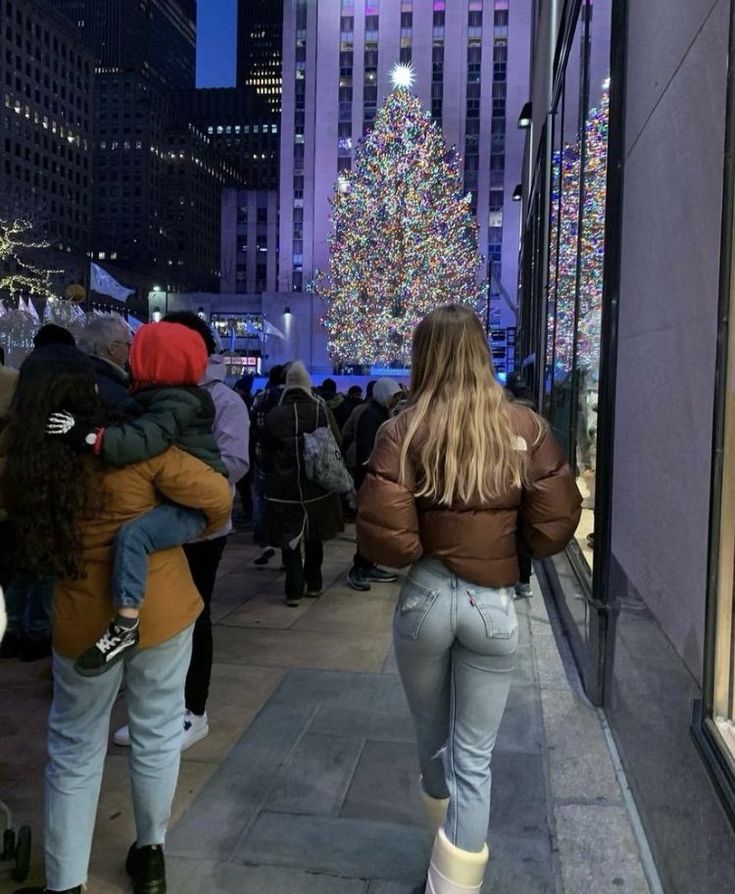 Blonde woman in brown jacket near Rockefeller Christmas tree